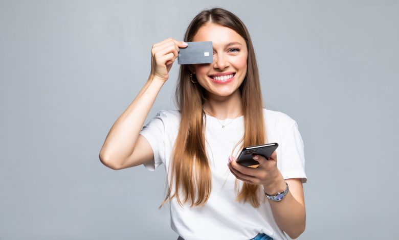 cheerful excited young woman with mobile phone and credit card